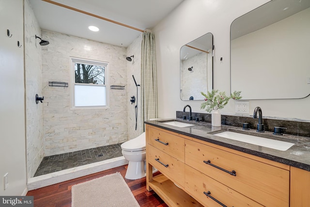 bathroom featuring tiled shower, a sink, and wood finished floors