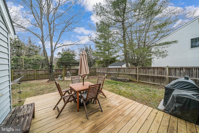 deck featuring a fenced backyard, outdoor dining area, and a lawn