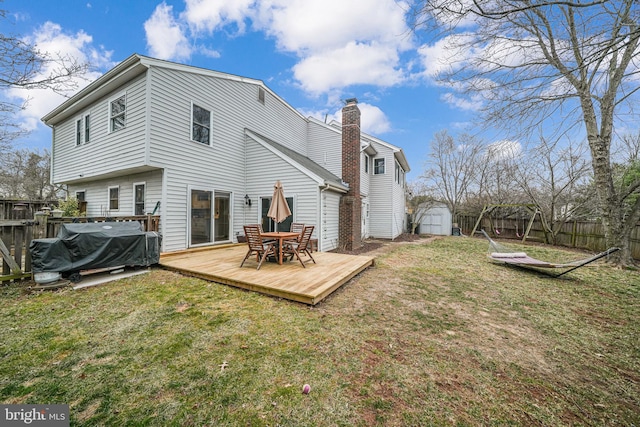 back of house with an outbuilding, fence, a lawn, a wooden deck, and a shed