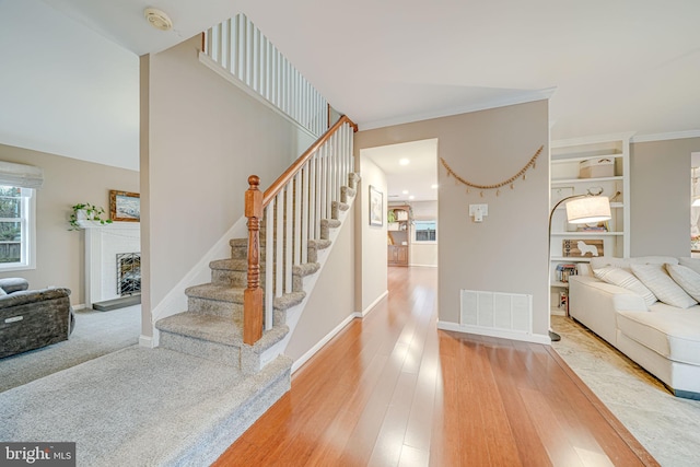 interior space featuring baseboards, visible vents, a fireplace with raised hearth, and wood finished floors