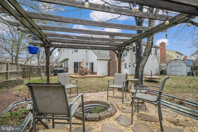 view of patio / terrace featuring a storage shed, an outdoor fire pit, an outbuilding, a wooden deck, and a pergola