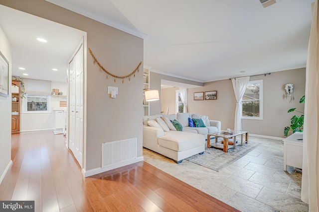 living room with light wood finished floors, baseboards, visible vents, ornamental molding, and recessed lighting