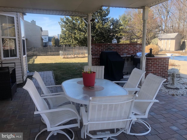 view of patio / terrace featuring a storage shed, fence, outdoor dining area, and an outdoor structure