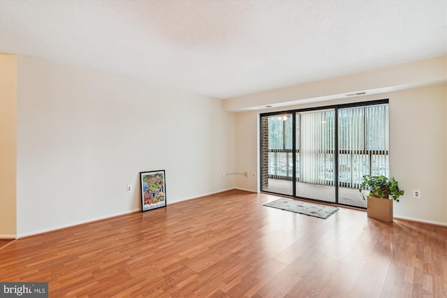 unfurnished room with light wood-type flooring, visible vents, and baseboards