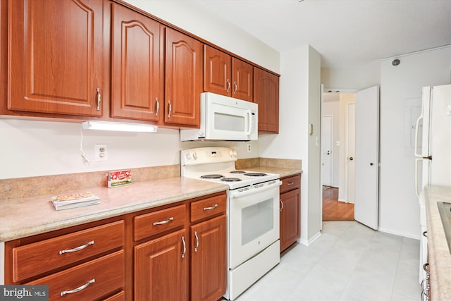 kitchen featuring brown cabinets, white appliances, light countertops, and baseboards