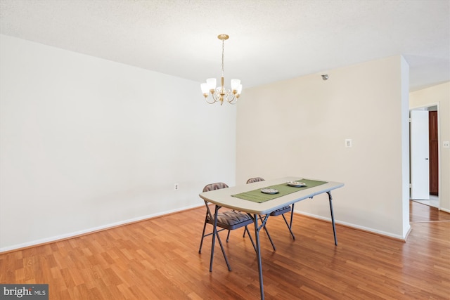 dining area featuring a textured ceiling, an inviting chandelier, wood finished floors, and baseboards