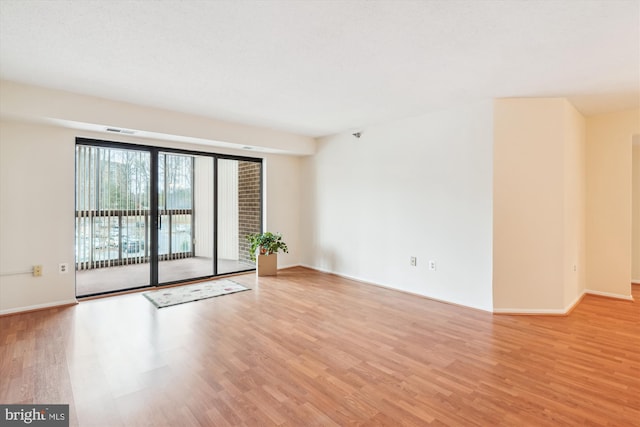 unfurnished room with light wood finished floors, visible vents, and baseboards