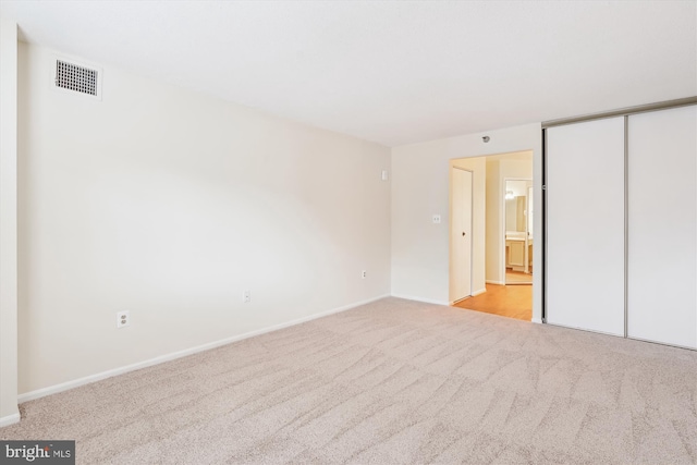 unfurnished bedroom with light carpet, a closet, visible vents, and baseboards