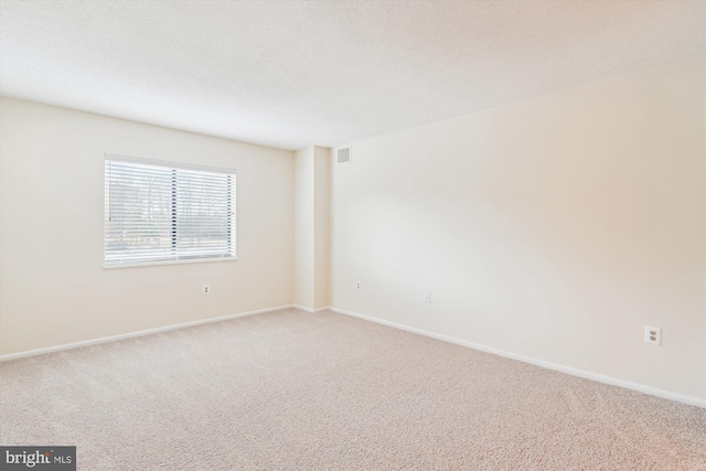 carpeted empty room featuring visible vents, a textured ceiling, and baseboards