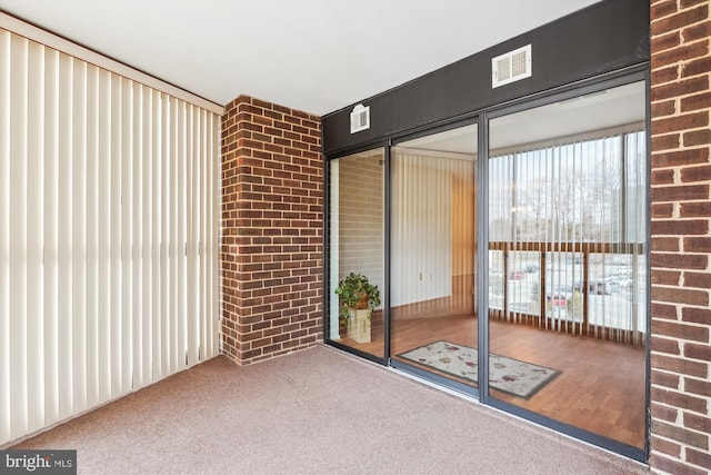 carpeted spare room featuring a wealth of natural light and visible vents