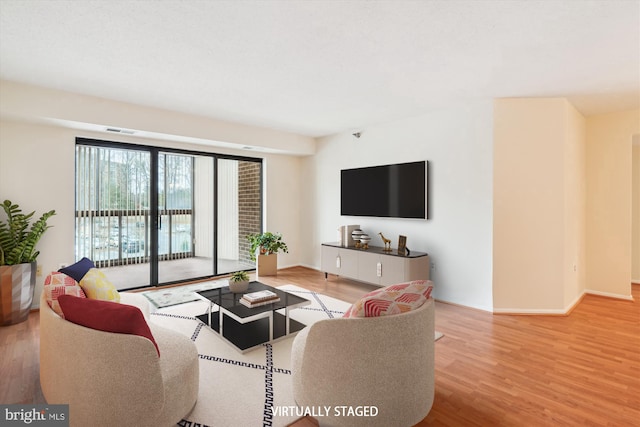 living room featuring visible vents, baseboards, and wood finished floors