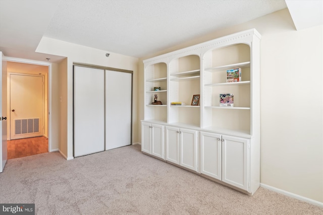 unfurnished bedroom with light carpet, a closet, visible vents, and baseboards