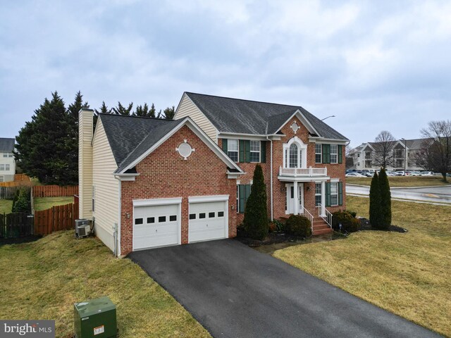 view of front of home featuring brick siding, fence, aphalt driveway, and a front yard