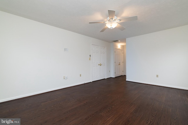 unfurnished room featuring dark wood-style floors, baseboards, visible vents, and a ceiling fan