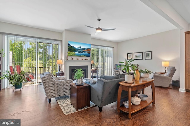 living room with dark wood-type flooring, ceiling fan, and a healthy amount of sunlight