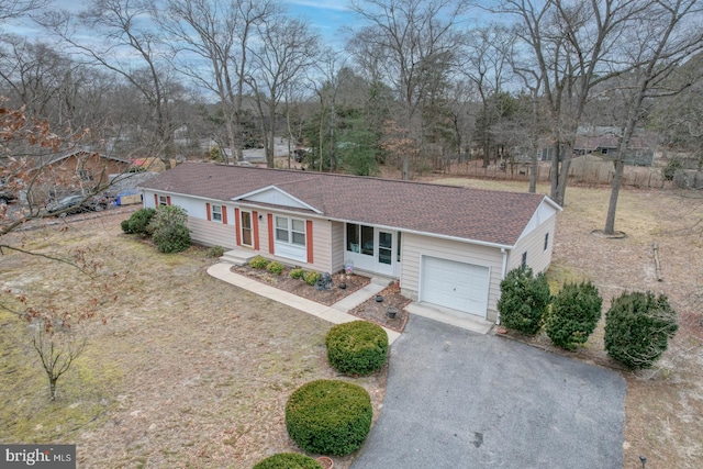 ranch-style home featuring a garage, aphalt driveway, and roof with shingles