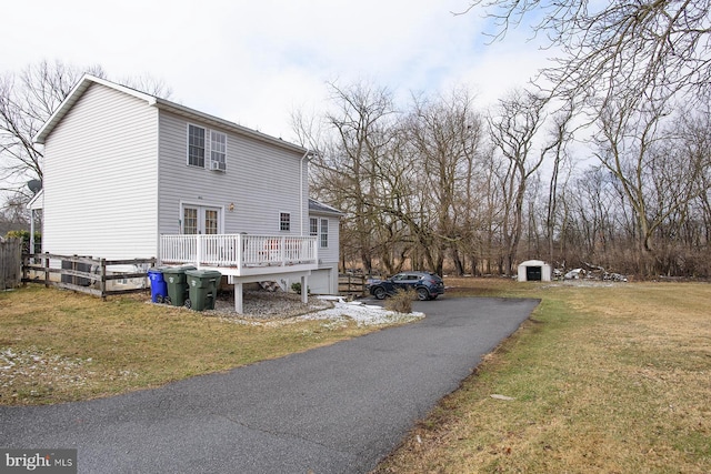 view of side of home featuring a wooden deck, a yard, and a shed