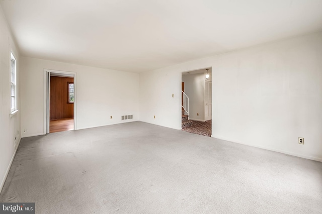 carpeted spare room featuring stairs and visible vents