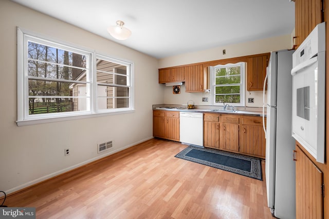 kitchen featuring light wood-style flooring, baseboards, white appliances, and visible vents