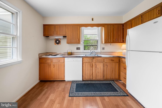kitchen featuring light wood-style floors, white appliances, light countertops, a sink, and baseboards