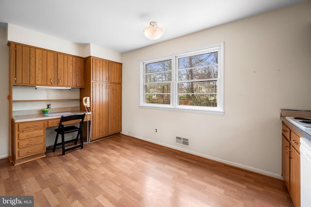 office space with baseboards, light wood finished floors, built in study area, and visible vents