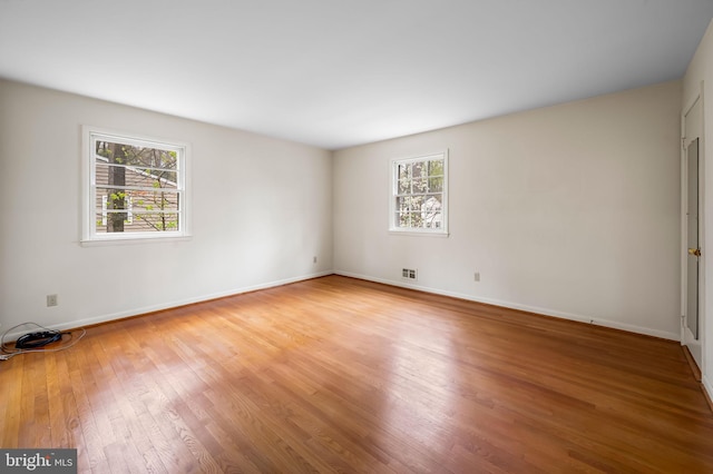 spare room featuring visible vents, light wood-style flooring, and baseboards