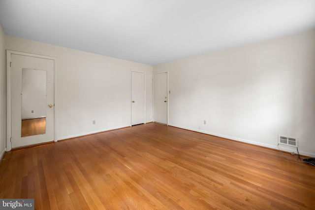 empty room featuring light wood finished floors, visible vents, and baseboards