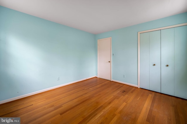 unfurnished bedroom featuring a closet, baseboards, and wood finished floors