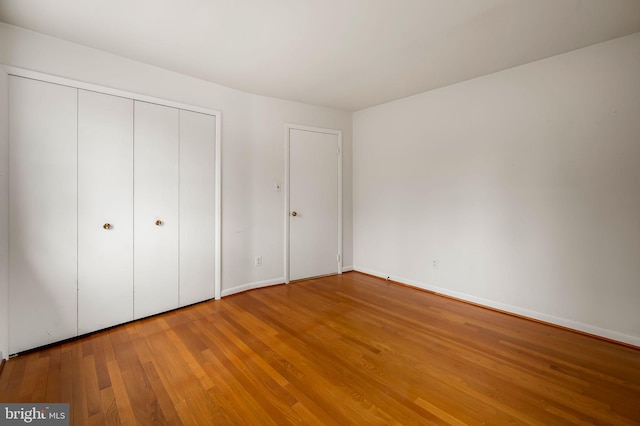 unfurnished bedroom featuring a closet, baseboards, and hardwood / wood-style floors