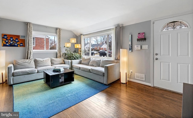 living area with vaulted ceiling, hardwood / wood-style flooring, visible vents, and baseboards