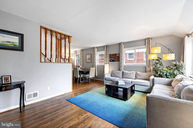 living room with baseboards, visible vents, vaulted ceiling, and wood finished floors