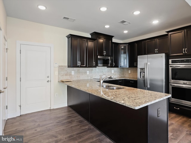 kitchen featuring dark hardwood / wood-style floors, sink, backsplash, light stone counters, and stainless steel appliances
