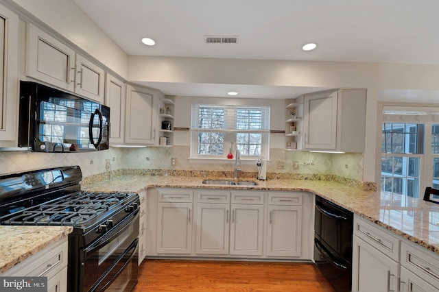 kitchen featuring visible vents, a sink, black appliances, and open shelves