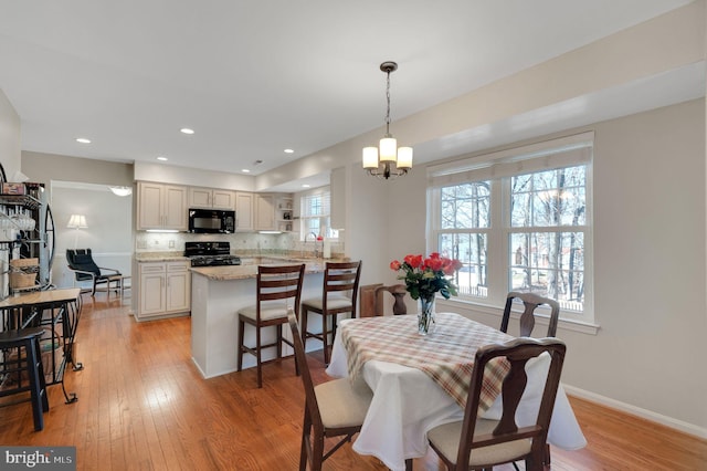 dining area featuring light wood-type flooring, a healthy amount of sunlight, and baseboards