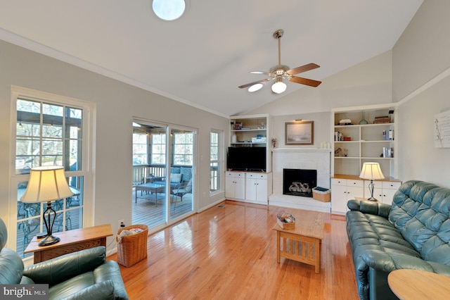 living room featuring ceiling fan, lofted ceiling, light wood-style floors, a brick fireplace, and crown molding