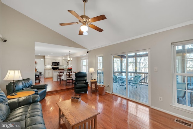 living room with high vaulted ceiling, a ceiling fan, visible vents, baseboards, and light wood finished floors