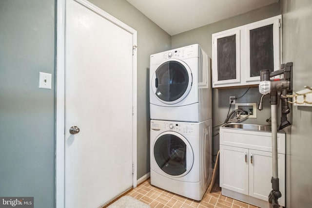 laundry area featuring a sink, stacked washing maching and dryer, and cabinet space