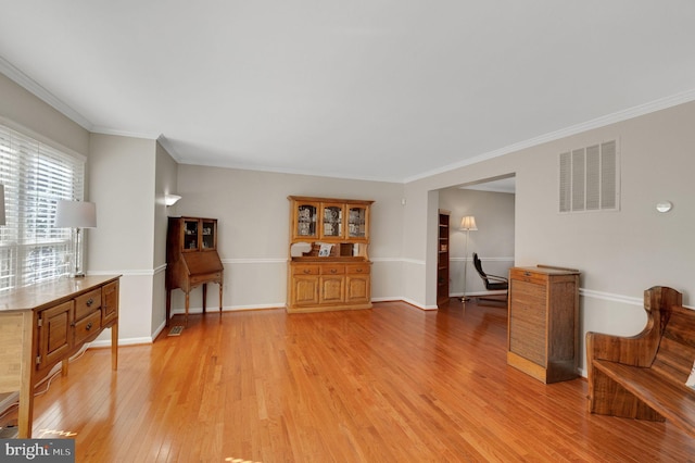 living room with light wood finished floors, baseboards, visible vents, and ornamental molding