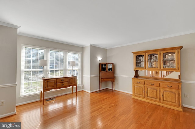 sitting room featuring baseboards, crown molding, and light wood-style floors