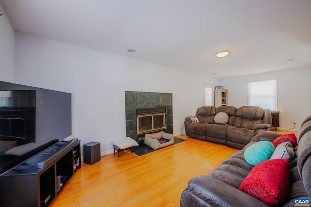 living room with a tiled fireplace and hardwood / wood-style flooring