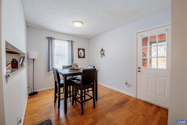 dining area with light hardwood / wood-style floors and a textured ceiling