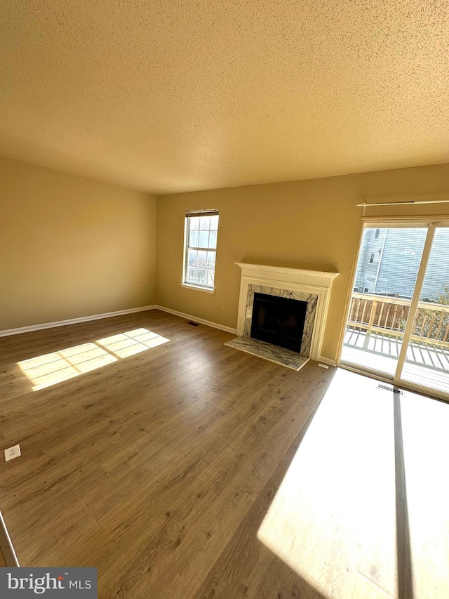 unfurnished living room with hardwood / wood-style flooring, a fireplace, and a textured ceiling