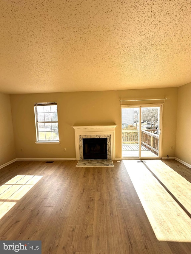 unfurnished living room with a high end fireplace, wood-type flooring, and a textured ceiling