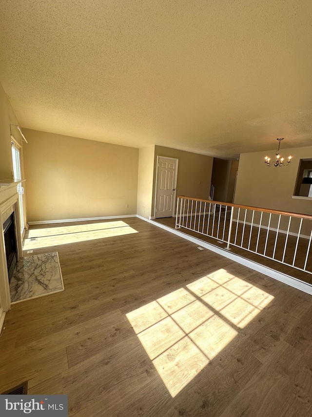 unfurnished living room with hardwood / wood-style floors, a notable chandelier, and a textured ceiling