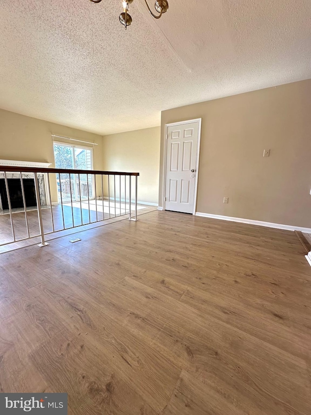 unfurnished living room with wood-type flooring and a textured ceiling