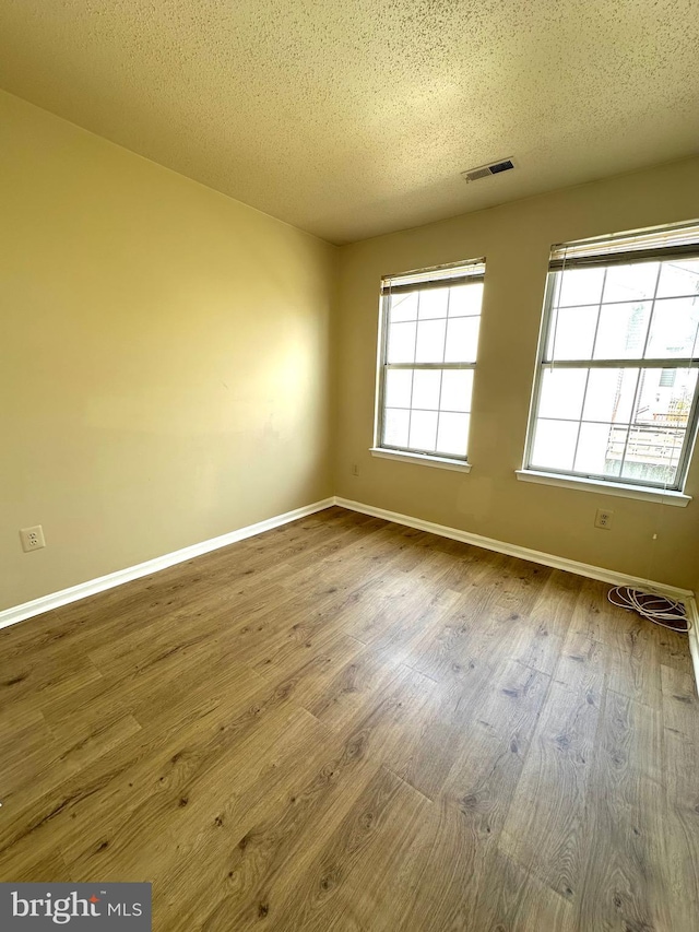 unfurnished room with wood-type flooring and a textured ceiling