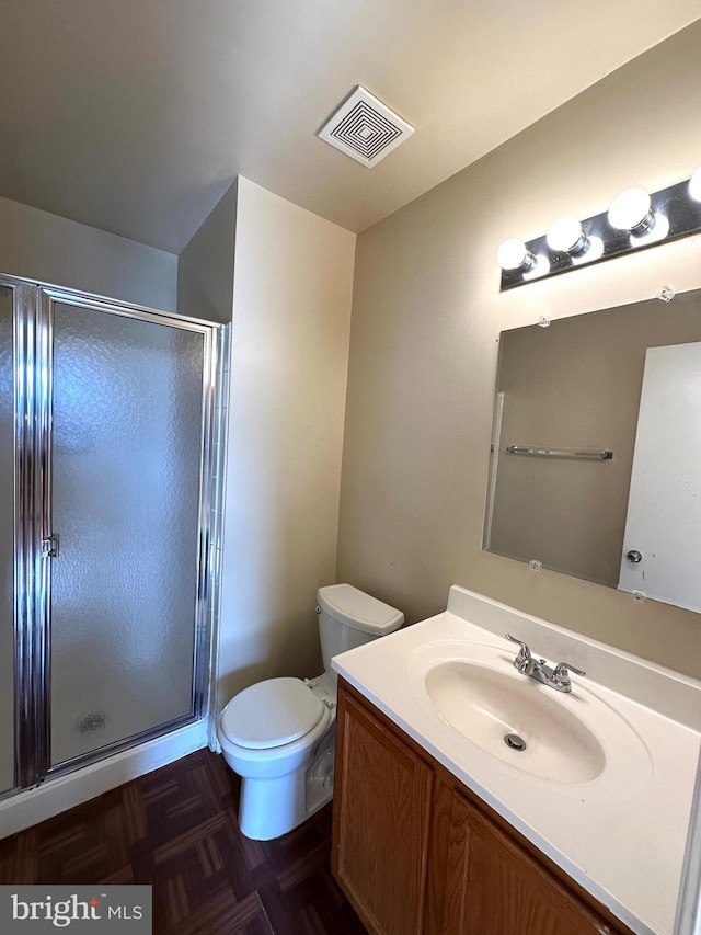 bathroom with a shower with door, vanity, parquet flooring, and toilet