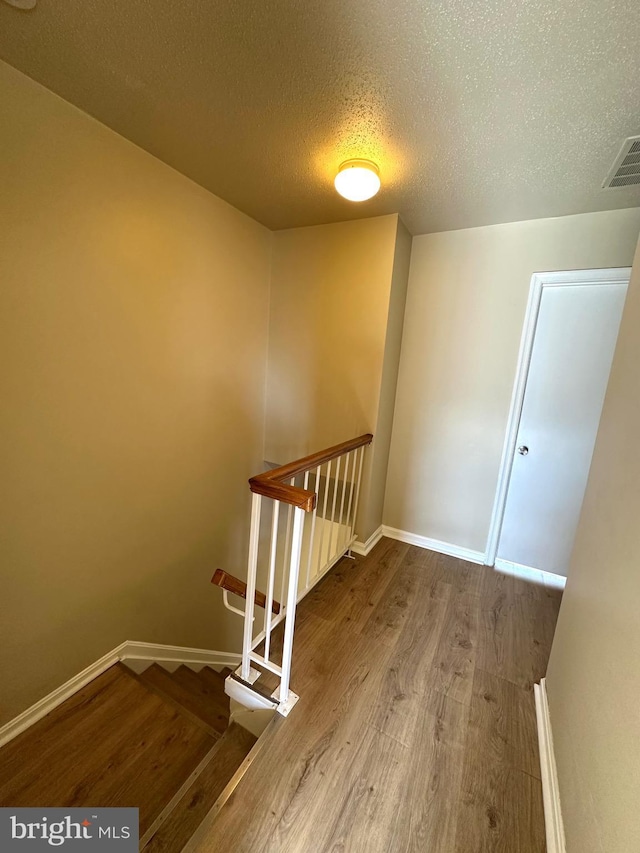 staircase featuring wood-type flooring and a textured ceiling