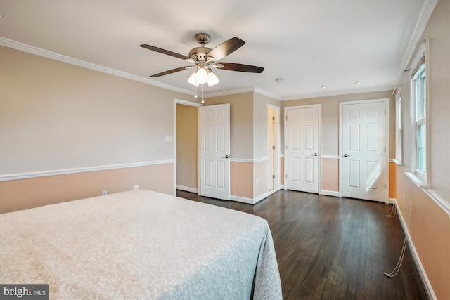 unfurnished bedroom with baseboards, a ceiling fan, dark wood-style floors, ornamental molding, and two closets