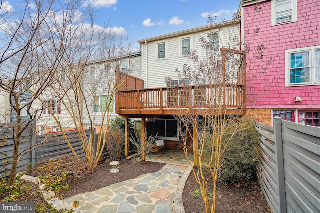 back of property featuring a wooden deck, fence, and a patio